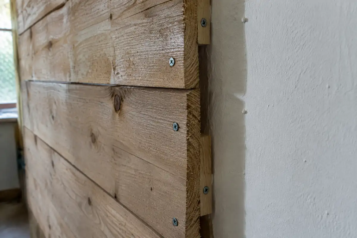 Lambris de bois brut vissé sur tasseaux, dont l'épaisseur dépasse du mur peint voisin